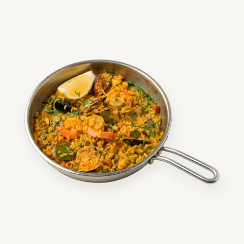 Seafood paella in a pan with lemon