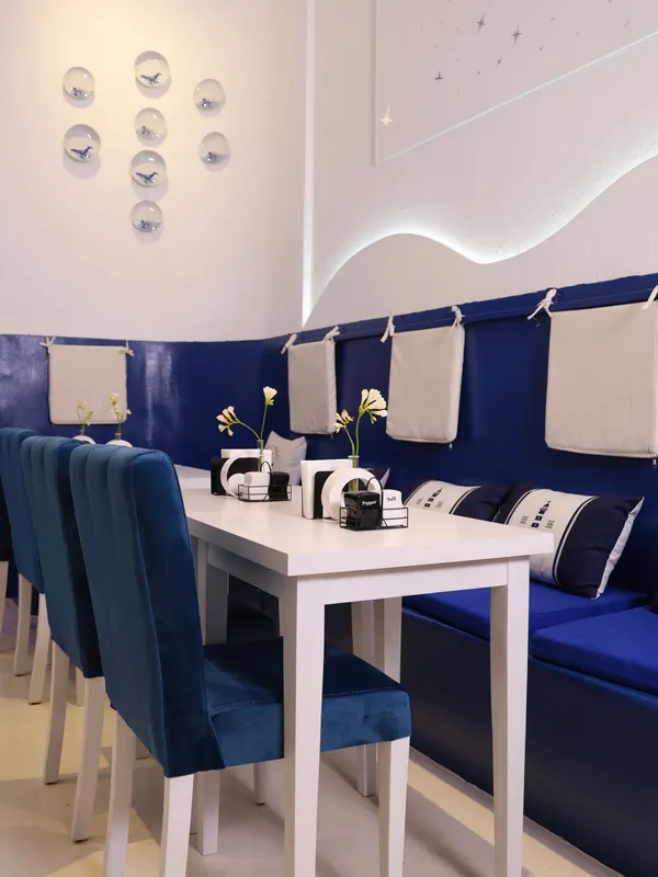 White tables, blue velvet chairs and a lit wave along the wall