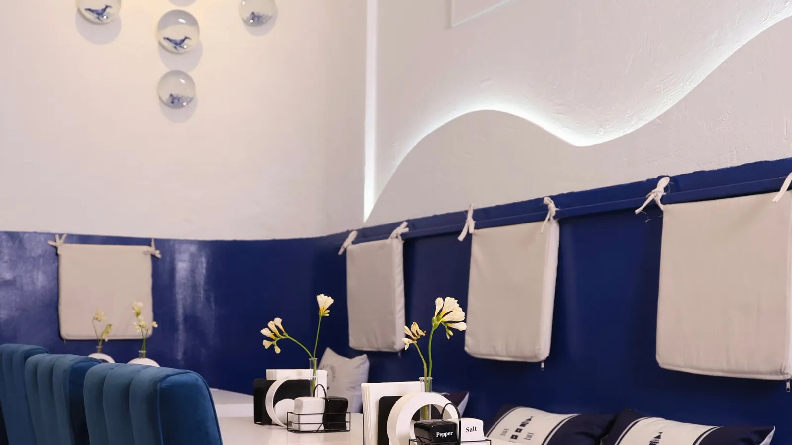 The hall of Kraken: a lit wave along the white wall, navy banquettes and blue velvet chairs