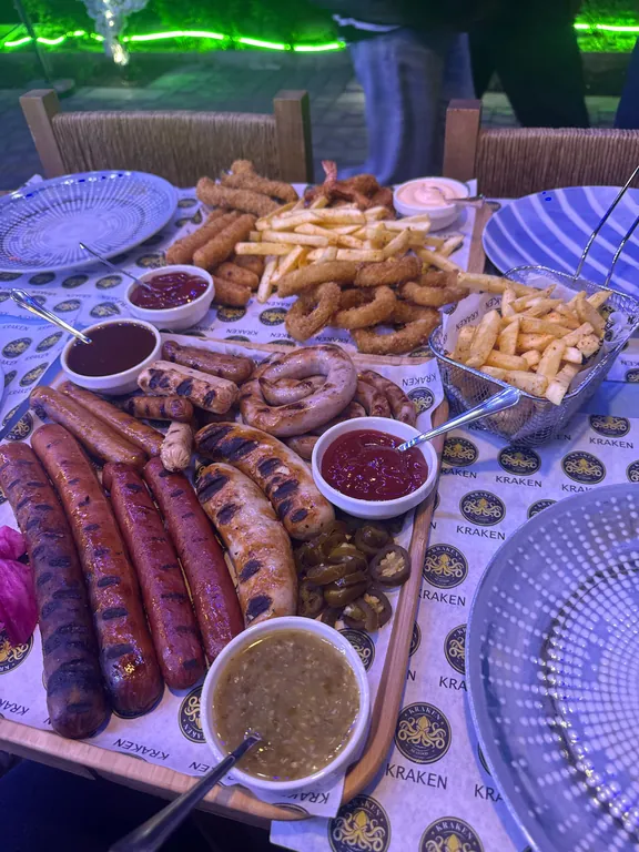 Grilled sausages, squid rings and fries on a Kraken tray