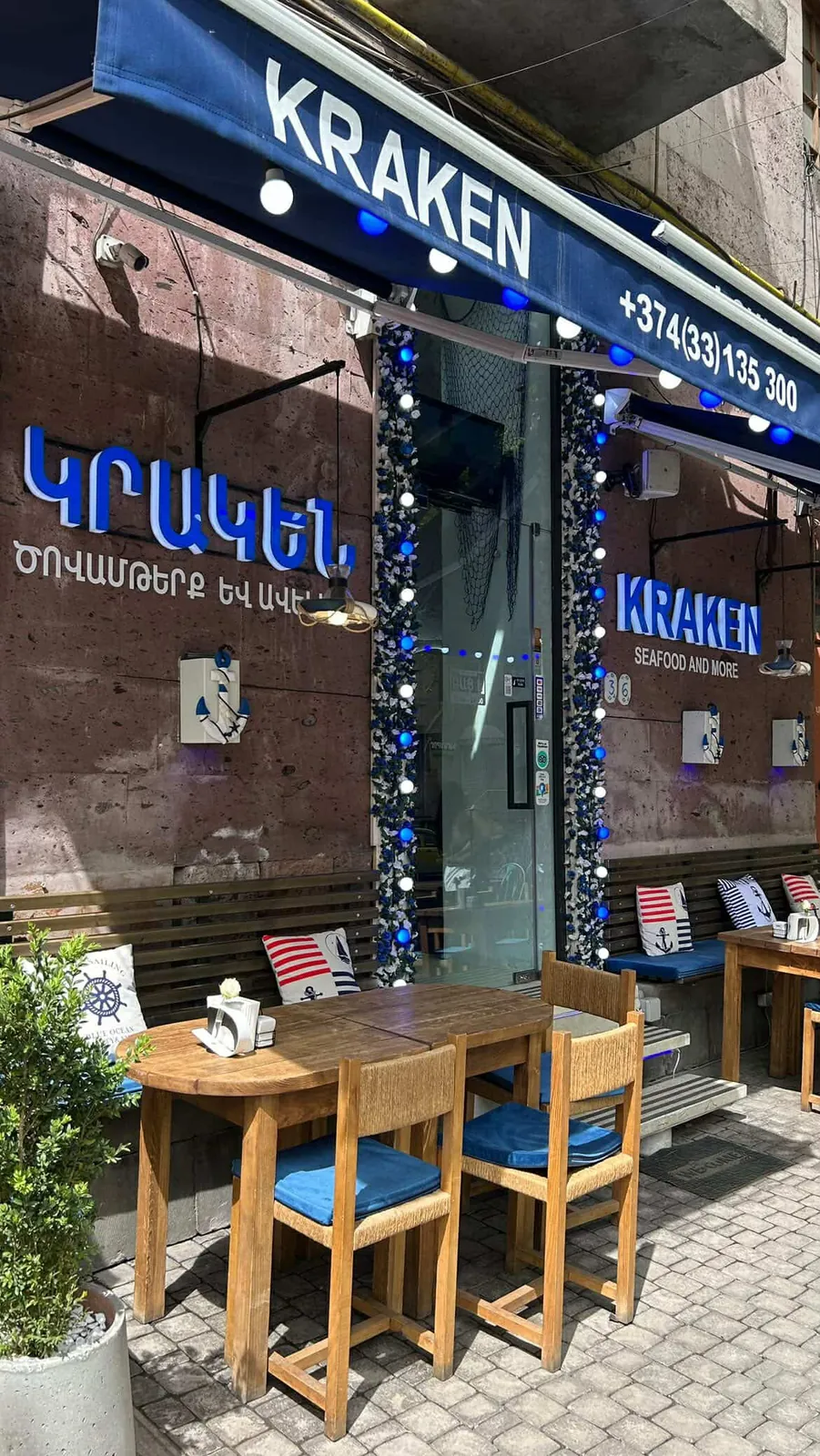 The terrace on Moskovyan Street: wooden tables, blue cushions and the KRAKEN awning